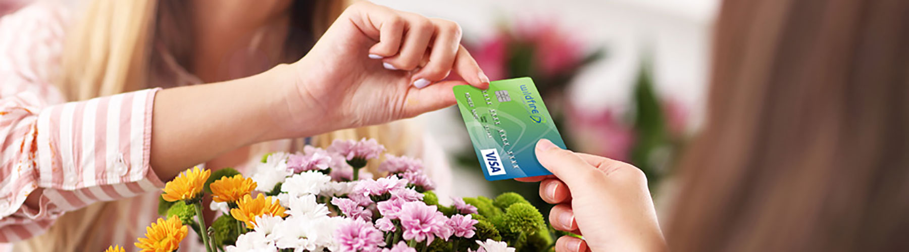Happy female paying for flowers with Wildfire Visa Credit Card