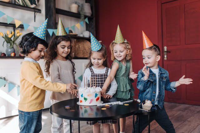 Kids celebrating wearing birthday hats and eating cake