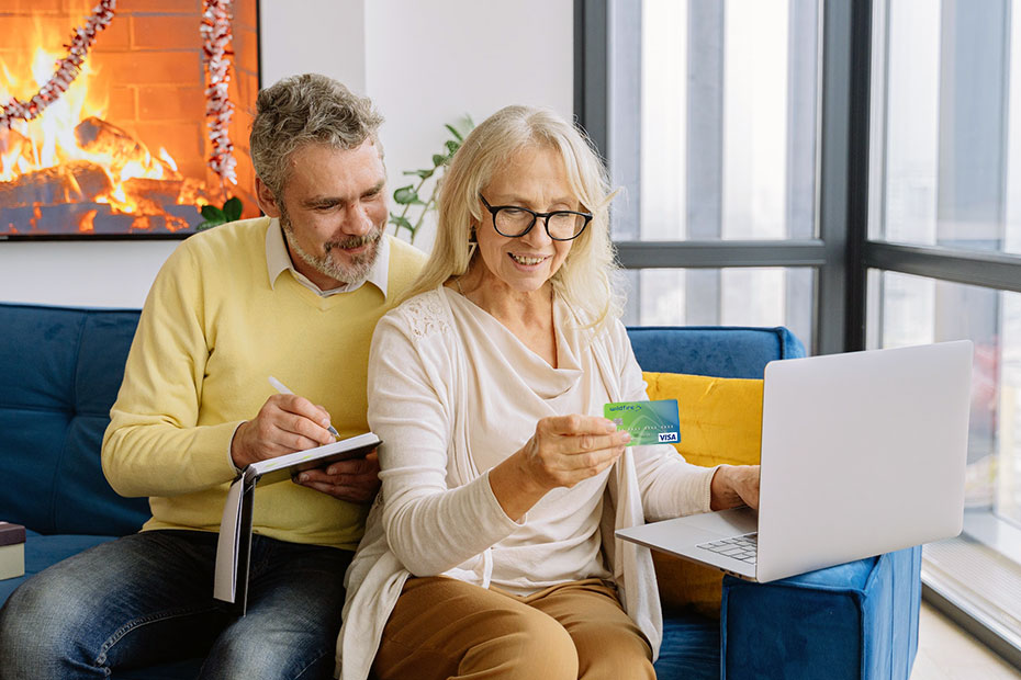 Elderly Couple happily looking at laptop and credit card Elderly Couple happily looking at laptop and credit card