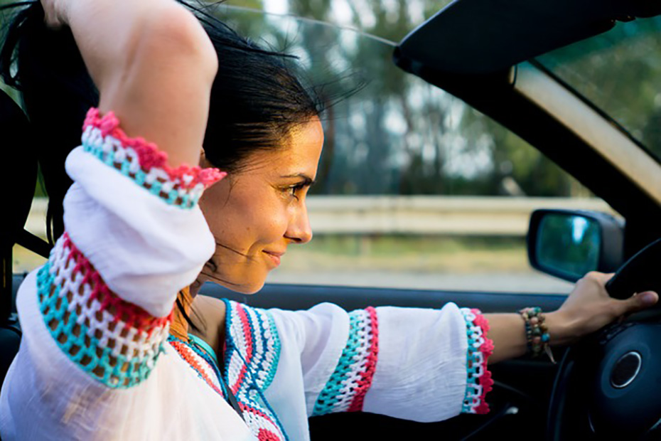 Female confidently driving a convertible car at sunset