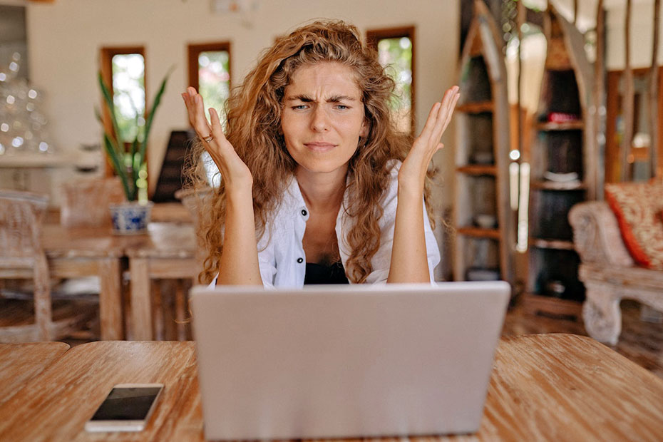 Frustrated woman using laptop at a kitchen table