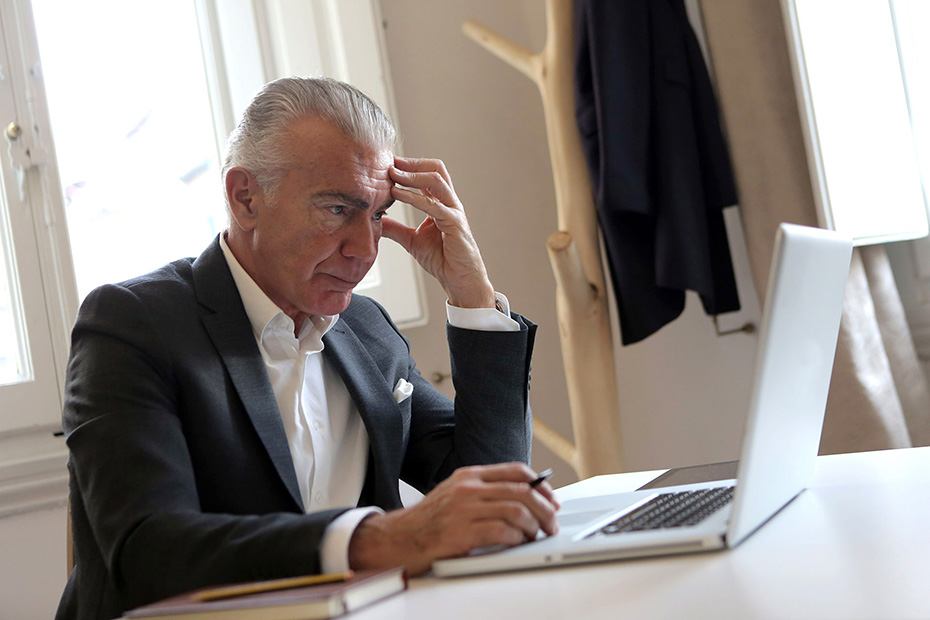 Senior male in Black Suit Jacket slightly stressed While Using Laptop