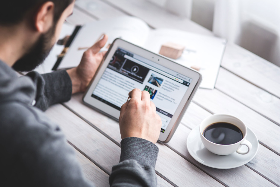 Man using a tablet at a table with a cup of coffee