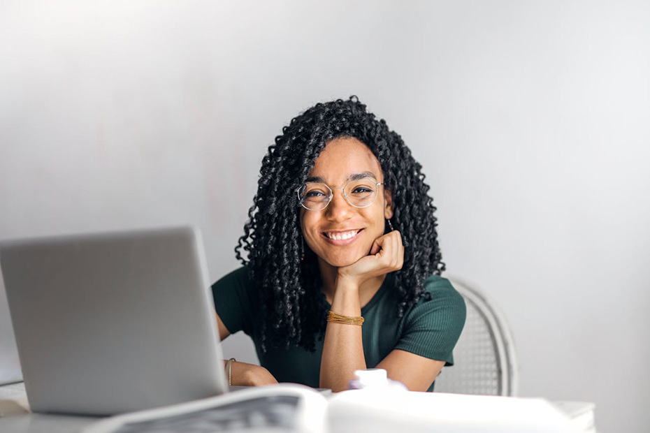 Smiling young woman with glasses working on a laptop