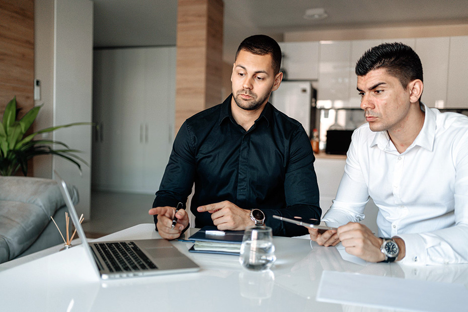 Two men working diligently on a laptop