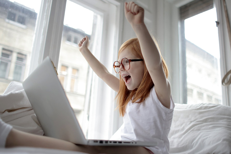 Young girl with red hair and glasses on a laptop cheering