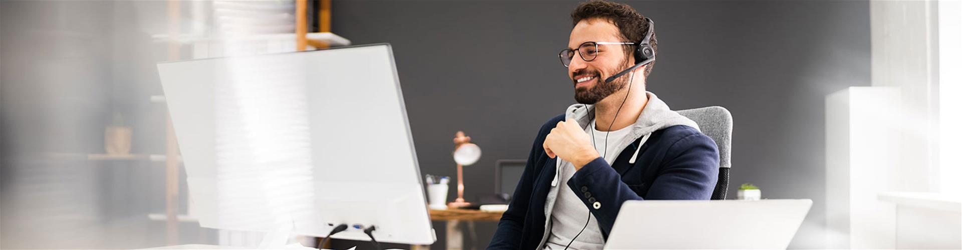 Adult male happily on desktop computer with headphones on