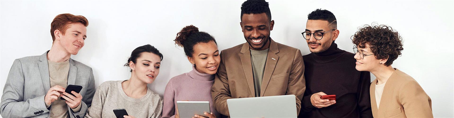 group of co-workers looking at laptop, tablet, and smartphones