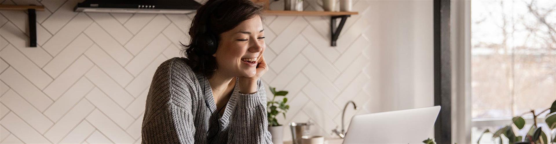 Happy Woman on computer in kitchen