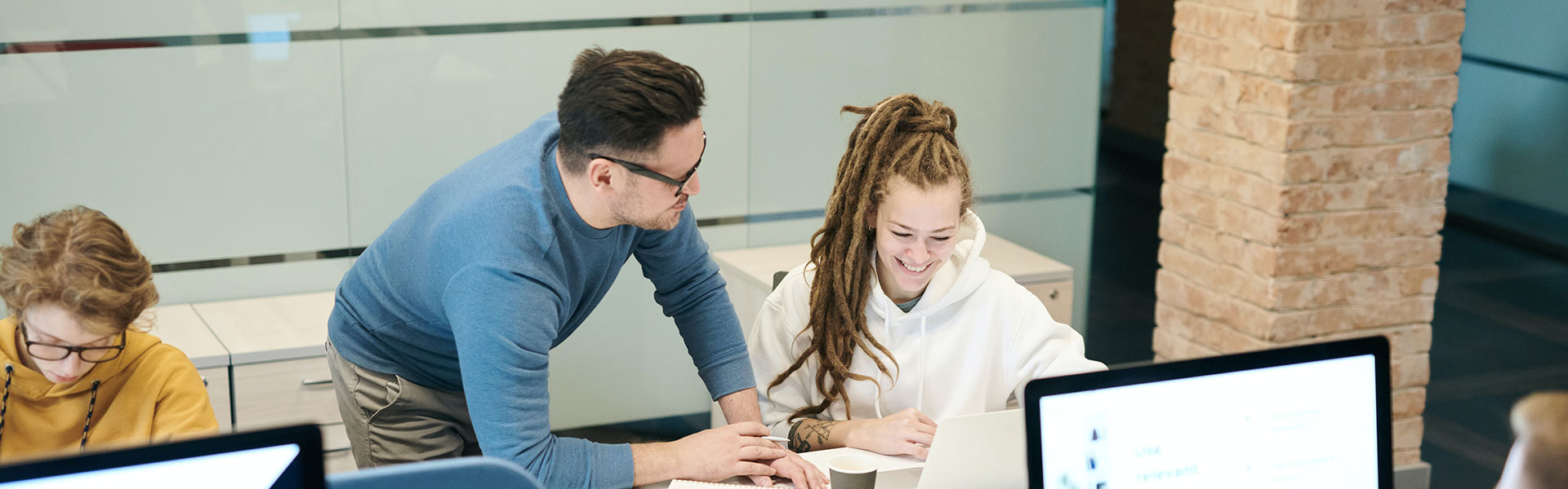 Man happily teaching woman about a computer