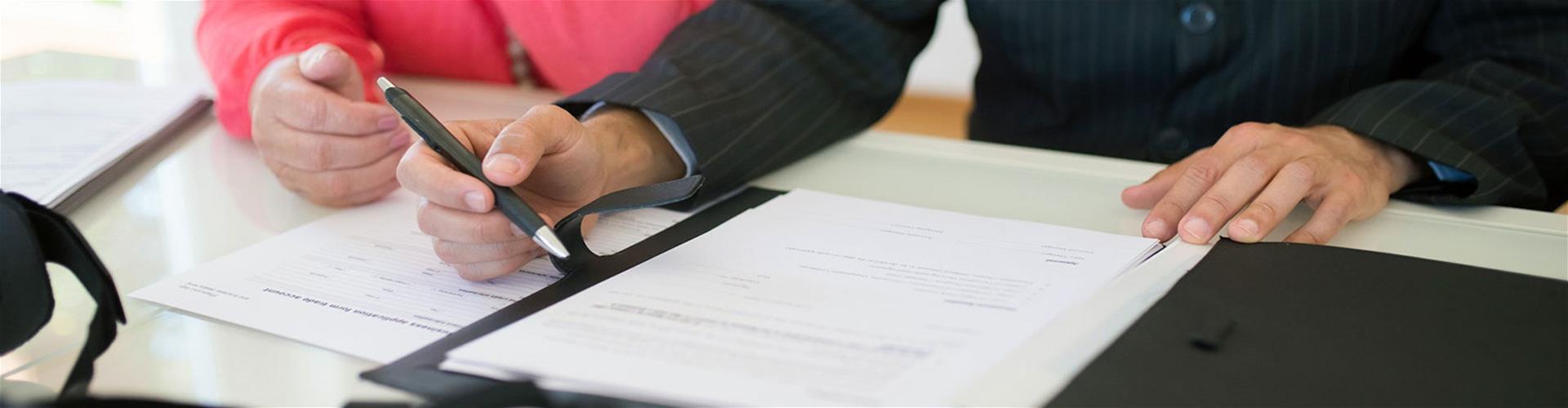 person holding a pen near a piece of paper