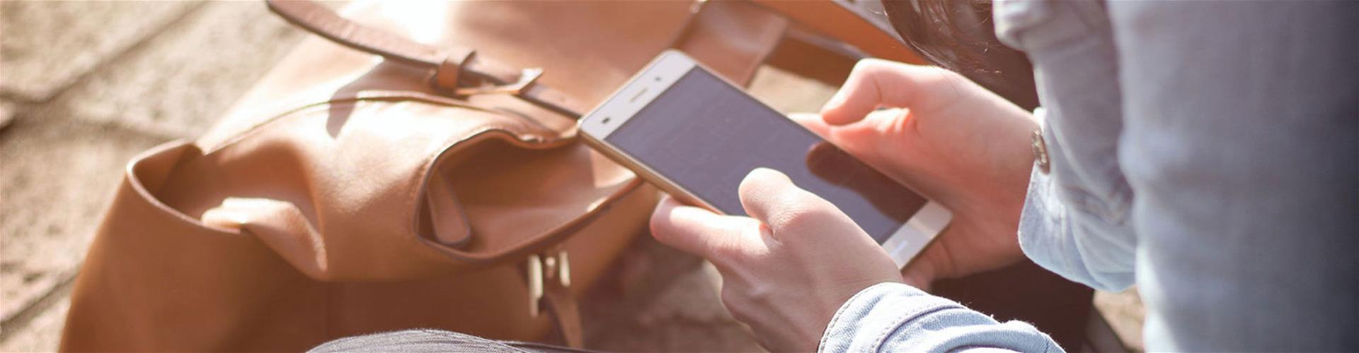 Person outside using smartphone while sitting down