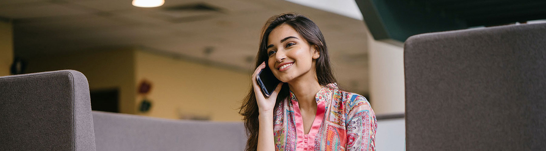 Smiling Woman in Floral Salwar Kameez Talking on Phone While Sitting