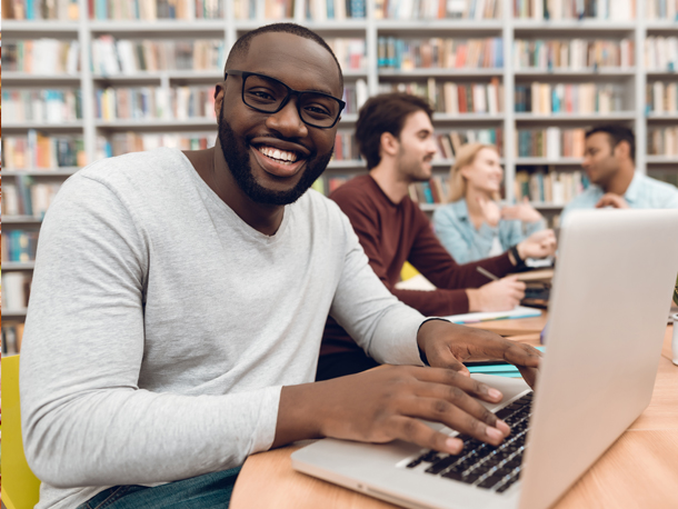 Cardinal Perks Membership Fee Waived Gentleman smiling at laptop while in the library