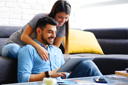 Happy couple working on computer together in a living room