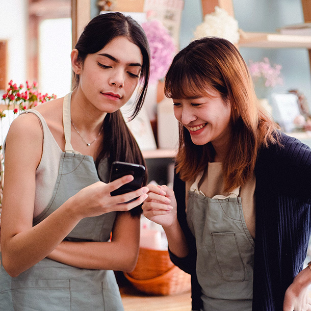 Happy Female coworkers with smartphone in floral shop