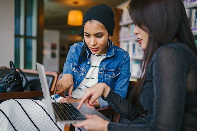 Two Women Looking And Pointing At Laptop