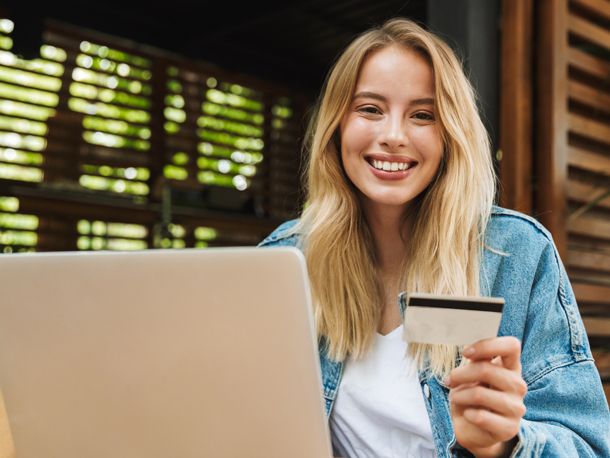 Debit Card makes buying stuff easy Happy Woman on computer with debit card in hands