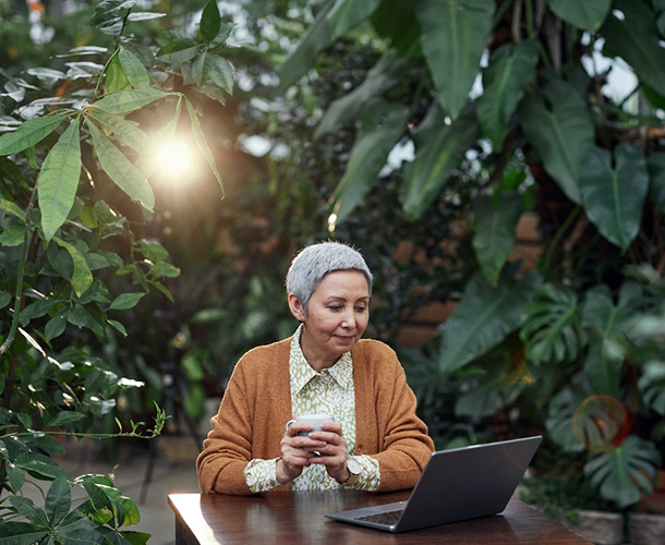woman looking at laptop in greenhouse woman looking at laptop in greenhouse
