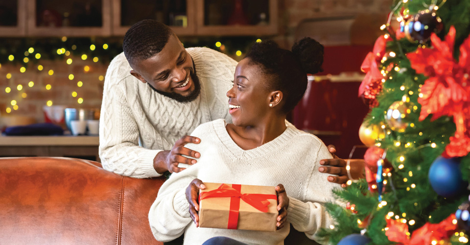 Happy young couple opening up gifts near a Christmas Tree