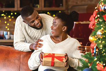 Happy young couple opening presents near a Christmas Tree