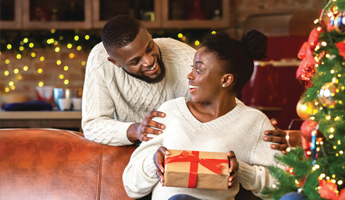 Happy young couple opening up gifts near a Christmas Tree