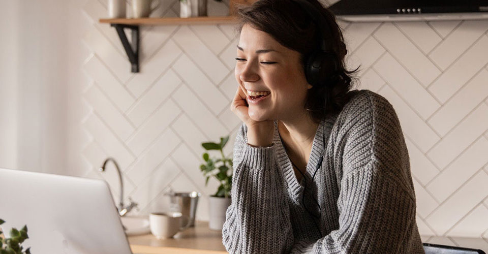 Happy woman using computer in kitchen