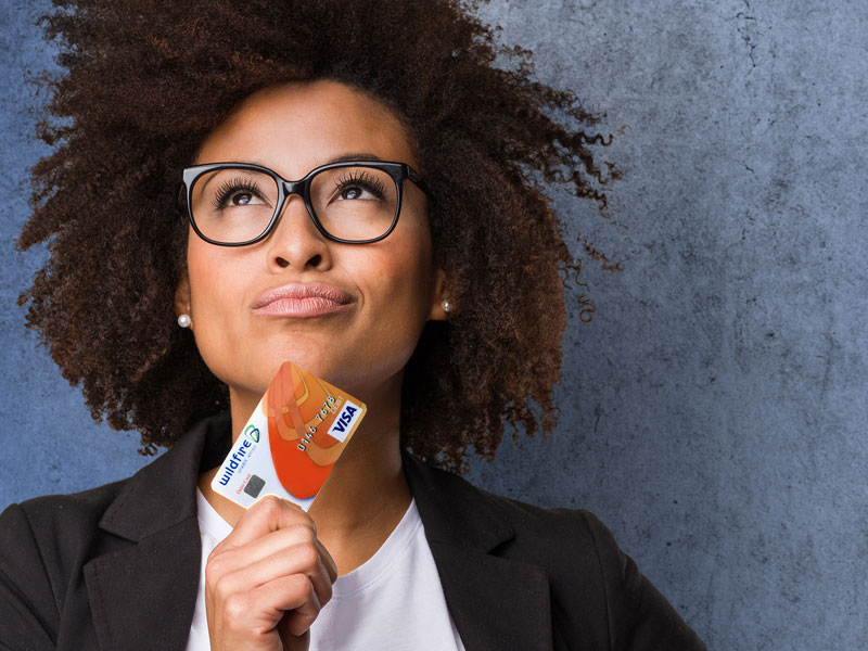 Businesswoman looking up confidently holding a Wildfire debit card