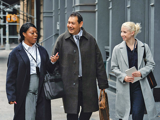 Business owner with employees happily walking down city street