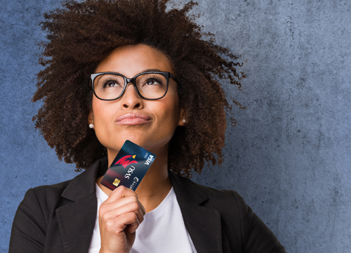 Businesswoman looking up confidently holding a Wildfire SVSU debit card