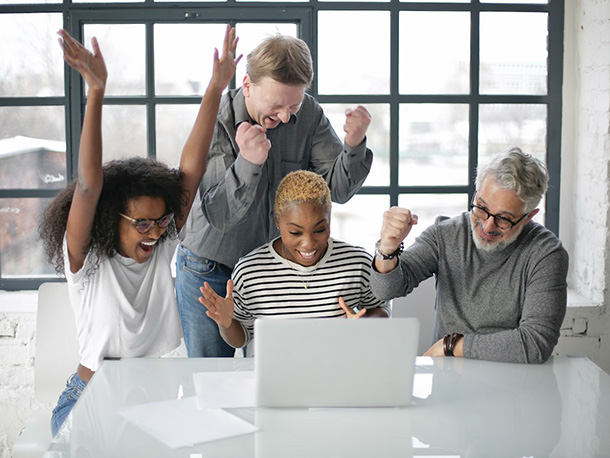 Group of employees in triumph in front of laptop