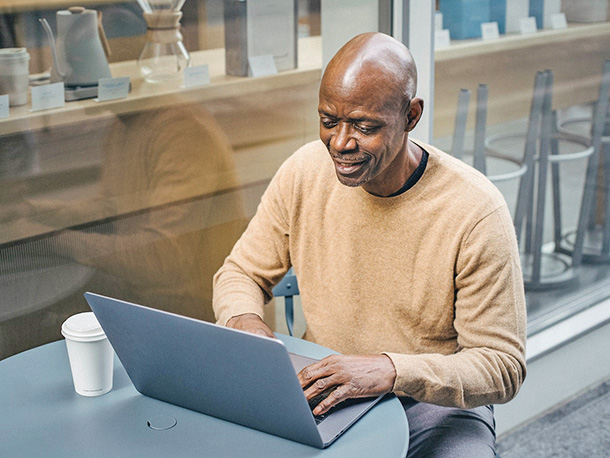 smiling businessman on laptop outside café smiling businessman on laptop outside café