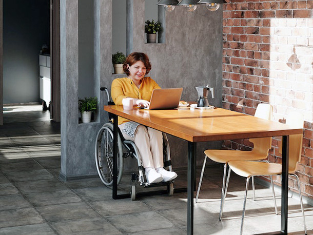woman in wheelchair using laptop in office