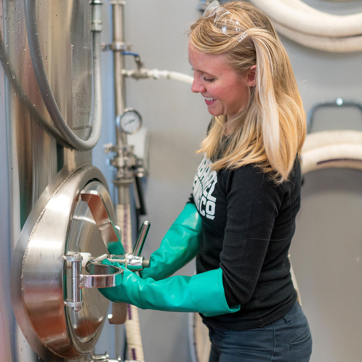 Woman in Black Shirt and Green Latex Gloves working with brewing equipment