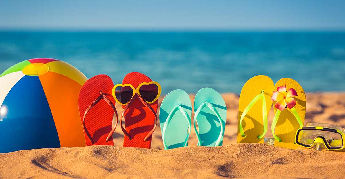 Colorful Sandals, beachball, and goggles in the sand on a beach