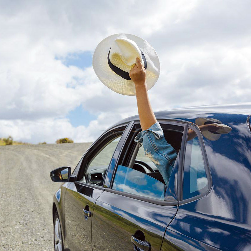 Person with hand out car window holding a hat Person with hand out car window holding a hat
