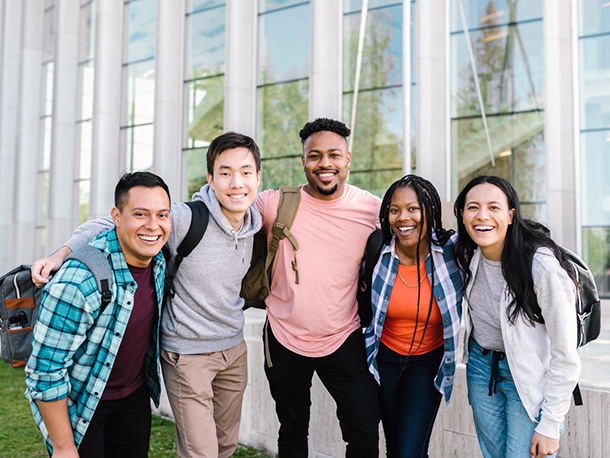 Happy College Students Standing Close Together outside campus building