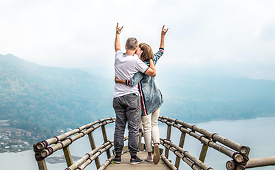 Retired couple on vacation standing on an overlook celebrating