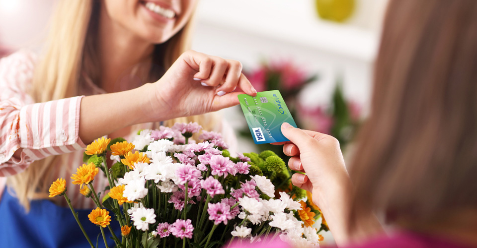 Happy female paying for flowers with Wildfire Visa Credit Card