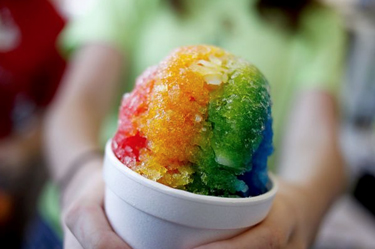 Person holding a rainbow snow cone
