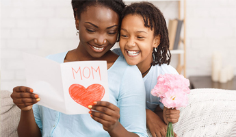 Smiling mom holding a card with happy young daughter