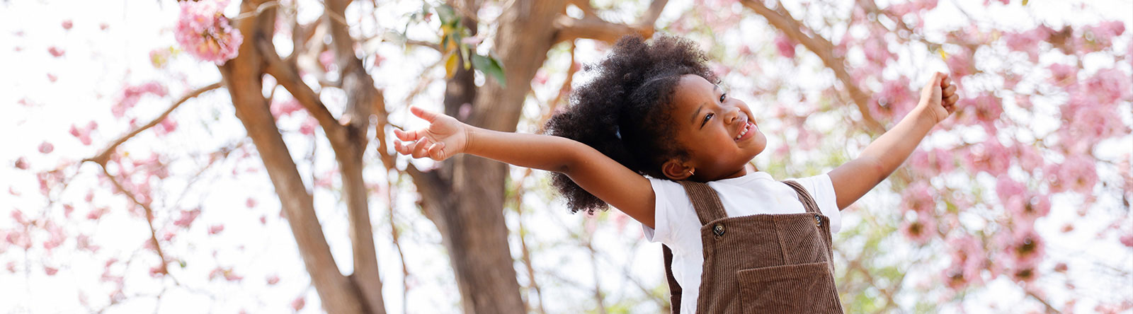 Young girl dancing oustide by tree with pink flowers