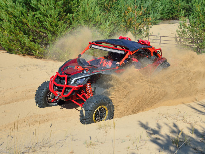 Off road vehicle driving through sand dunes by a forest