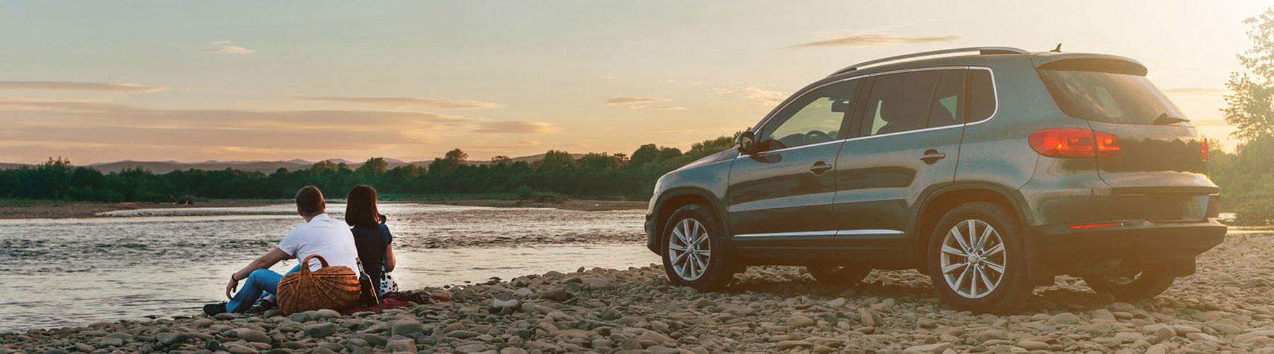 Couple sitting in front of Car parked on the beach