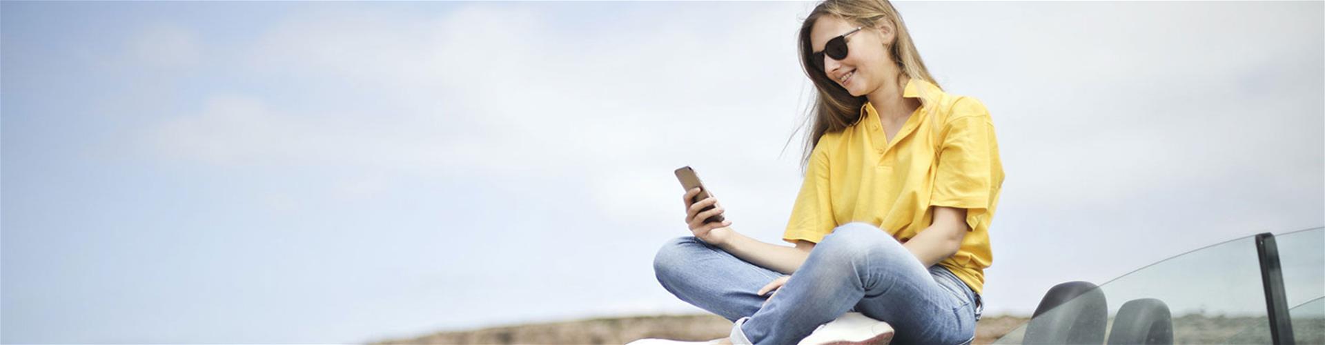 Happy woman sitting on top of car