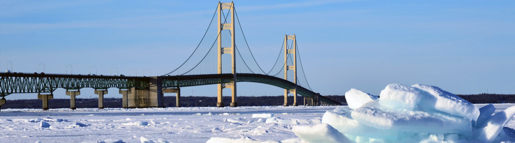 Mackinac Bridge in Winter during the day with frozen lake and ice chunks