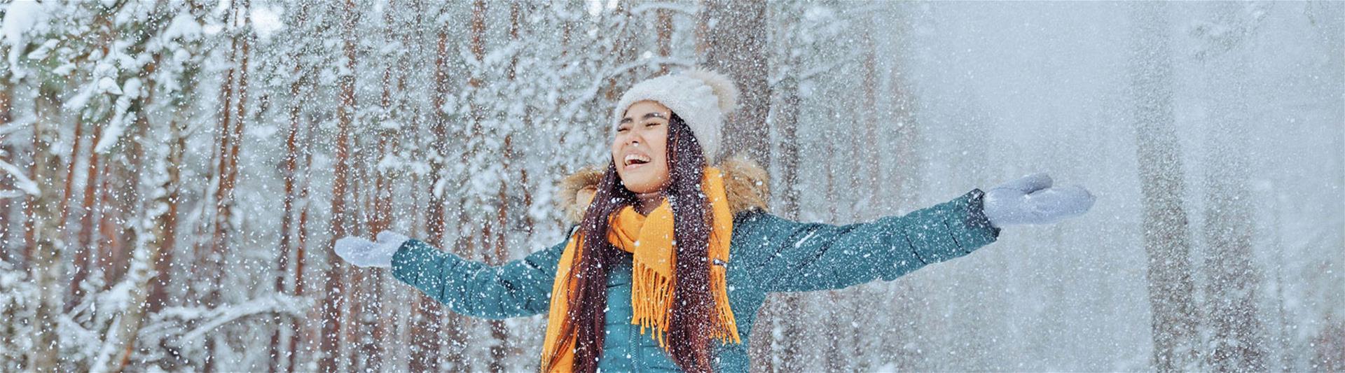 Woman in Green Jacket playing with Snow in forest