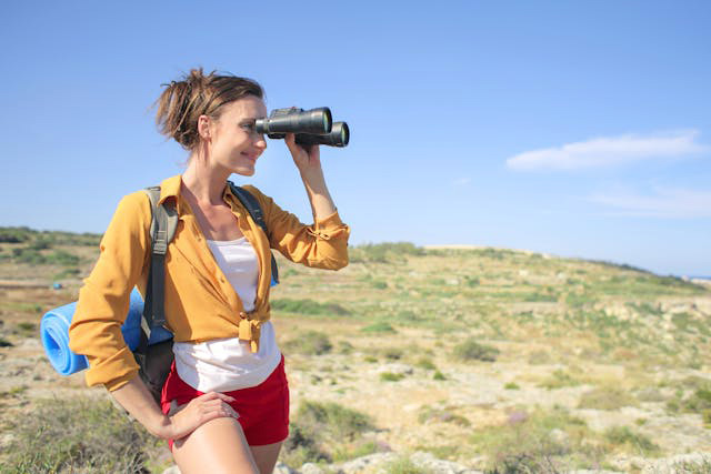 Female happily hiking and looking through binoculars.jpg