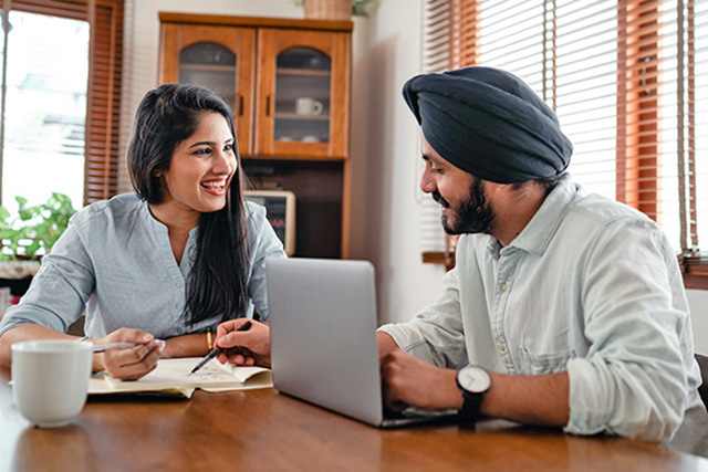 Happy couple sitting at a table with a laptop and documents