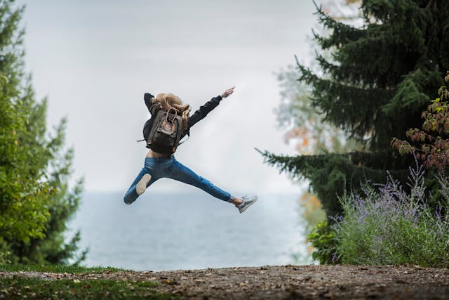 Female on a hiking trail in a forest jumping in the air
